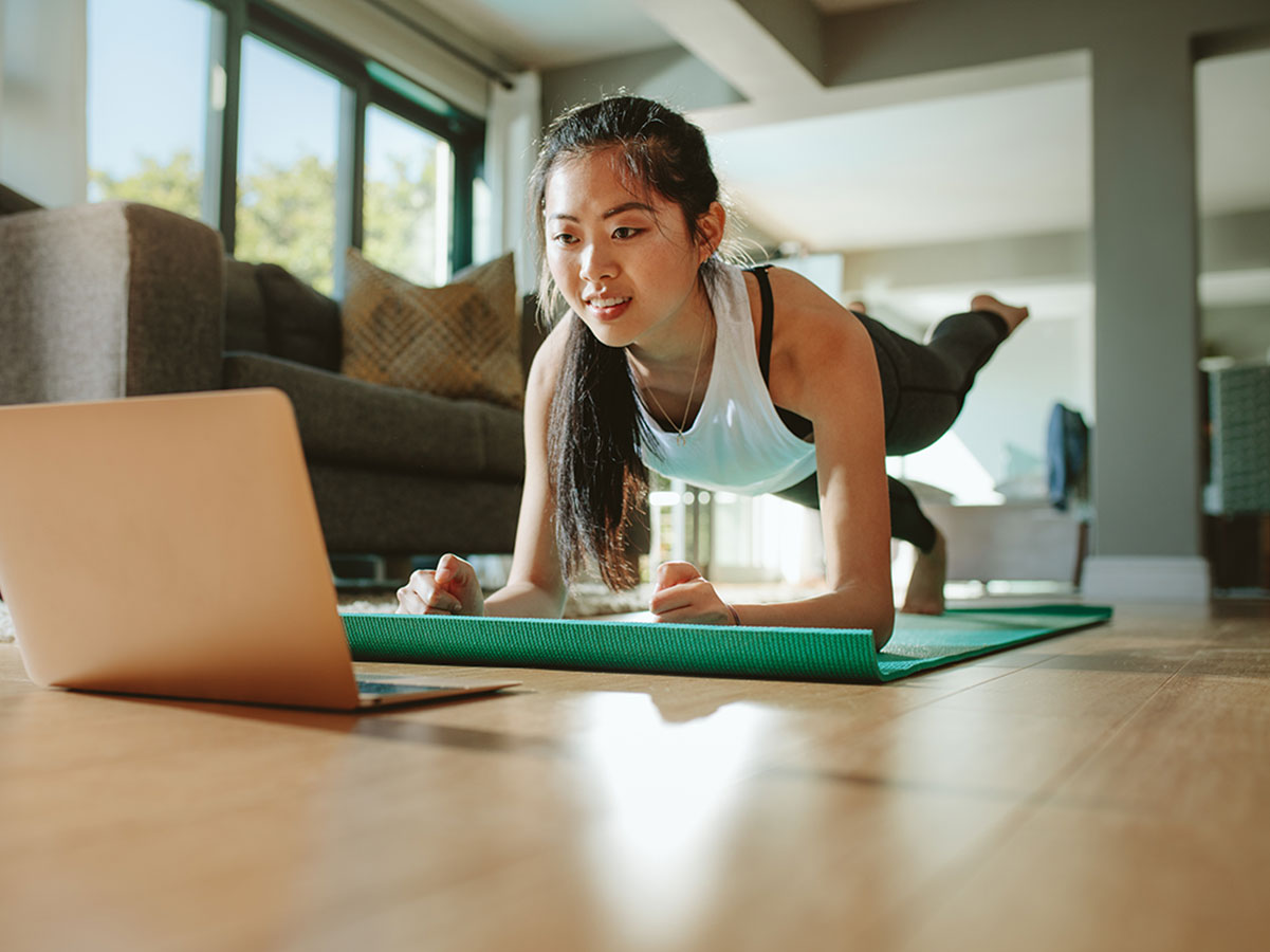 a woman is doing yoga while looking at a laptop with a relaxed look on her face